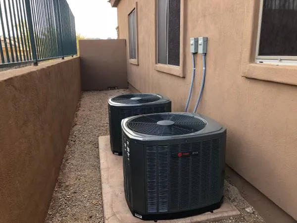 Two new split system condensers along a stucco wall